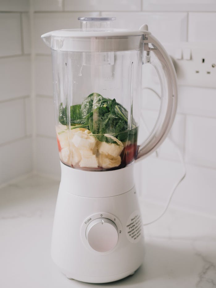 A blender filled with bananas, spinach, ready for a healthy smoothie.
