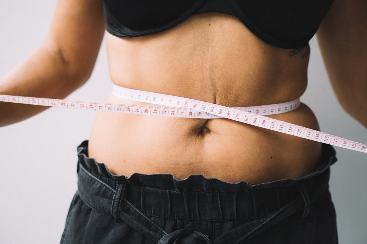 why-choose-us A person measuring their waist with a tape, symbolizing fitness and health goals.