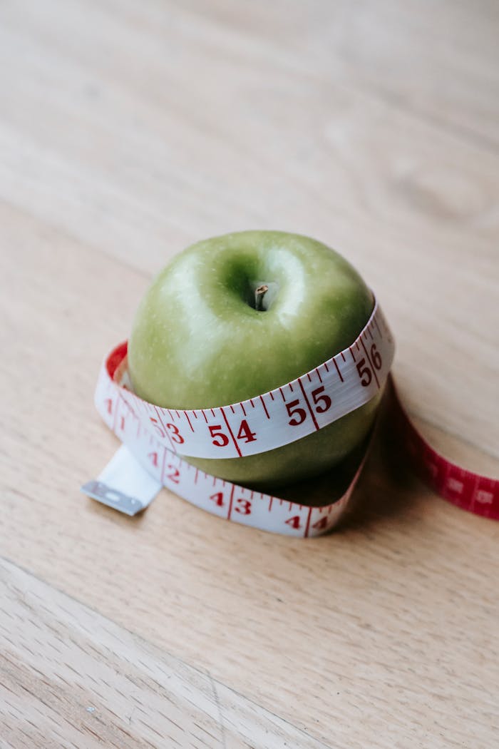 services-04 A green apple encircled by a measuring tape, symbolizing diet and fitness goals.