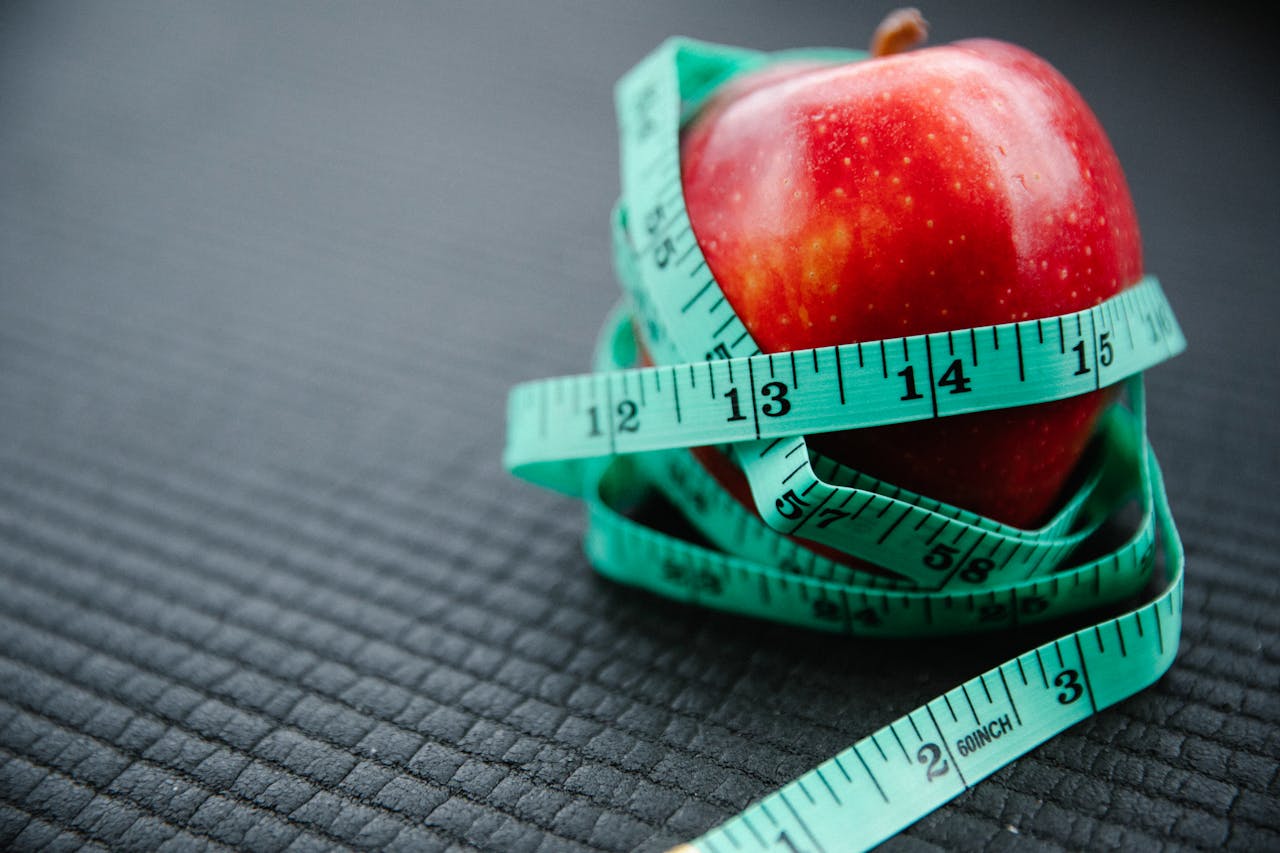 journey A vibrant red apple encircled by a blue measuring tape, symbolizing health and weight management.